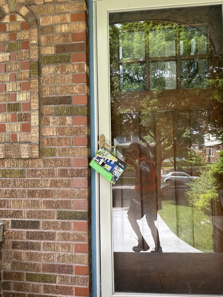 Glass front door with brick wall and hanging flyer