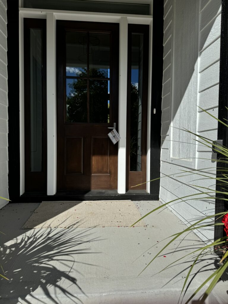Dark wood front door with white trim and glass sidelights